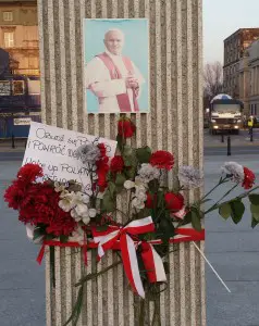 "Wake up Poland and return to God" - A message (from a concerned citizen) tied with flowers and a Polish-flag colored ribbon around the monument remembering PJP2's historic celebration of the mass and homily here in 1979.