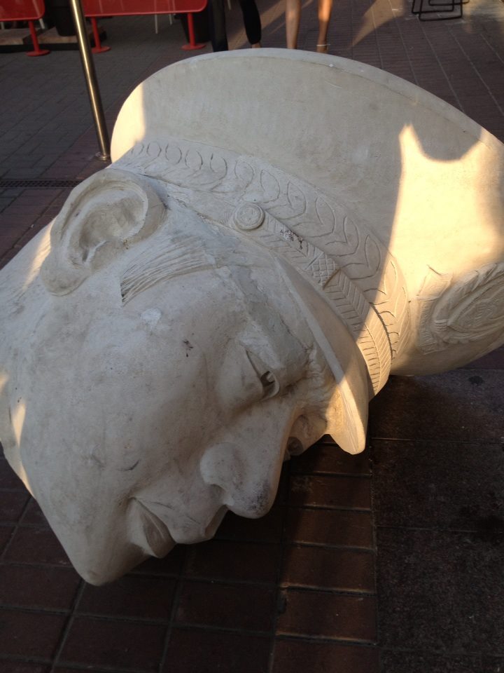 The severed head of a nameless and fictional dictator's statue lies on the sidewalk, greeting all visitors to the museum's entrance.