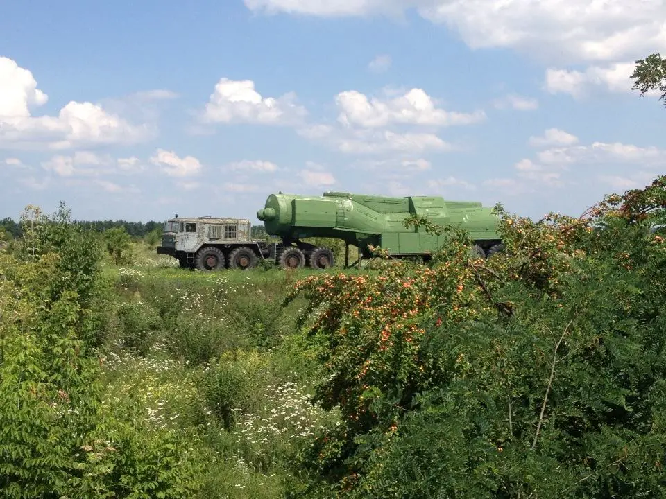 An image of the post-Soviet space: a rusting missile transport truck amidst the wildflowers and wild apricots of the countryside